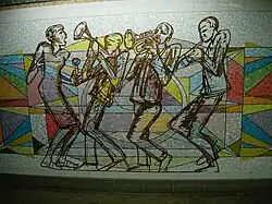 mosaïque représentant quatre silhouettes (trois joueurs de musique jazz et une danseuse) en contour noir, sur un fond géométrique coloré
