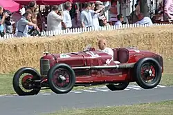 Photo d'une Alfa Romeo P2 rouge en pleine démonstration avec un conducteur au volant