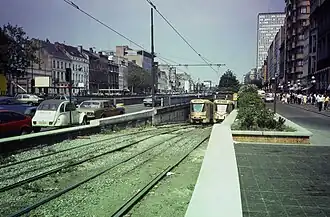 Un tram 18 en direction de  Fort Jaco sort du prémétro sur l'avenue de la Toison d'or et arrive à la place Louise. Il croise un tram 32 barré en direction de Jette avec en arrière-plan la porte de Namur (1985)
