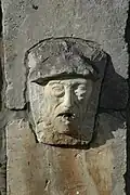 Photographie d'une fontaine représentant un visage d’homme surmonté d’un béret basque.