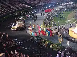 photo couleur d'une parade dans un stade olympique, prise depuis le haut des gradins