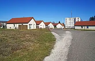 Un groupe de maisons récentes et une petite tour HLM derrière