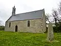 Chapelle de Sanspé : vue extérieure et stèle de l'Âge du fer.