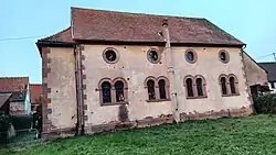 Façade sud portant des traces de balles, délimitée par un chainage d’angle en pierre de taille.