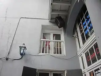 Vue extérieure d'un bâtiment, avec fenêtre de l'entresol en face et une baie vitrée à droite.