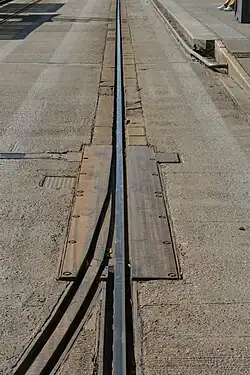 Un aiguillage sur la voie du TVR, à proximité de l'arrêt "Saint-Georges". Les deux rails étaient sur une plaque commune, qui pivotait en fonction du rail à aligner. Cet aiguillage était abandonné depuis 2005, et a en conséquence été soudé sur le rail encore en service.