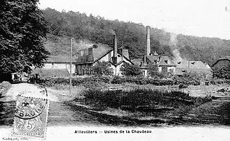 Photo noir et blanc montrant une petite usine avec deux cheminées carrées.
