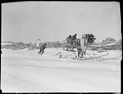 Photo en noir et blanc d'une structure d'avion autour de laquelle s'affairent plusieurs hommes.