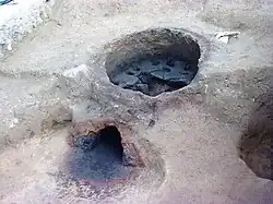 Photographie en couleurs d'une construction en terre en forme de dôme dont la partie supérieure a disparu.