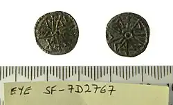 Photo des deux faces d'une pièce de monnaie portant des inscriptions des inscriptions en runes et en lettres latines arrangées en cercle autour du centre