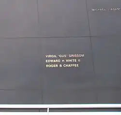 Photographie en couleur de noms gravés en doré sur un monument noir.