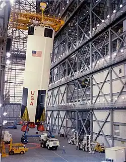 Plusieurs véhicules de service en dessous d'une partie de fusée en construction.