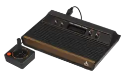 Console de jeux vidéo (boite noire et marron comportant des interrupteurs, avec une manette de jeu).