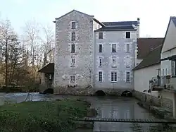 Vue d'un bâtiment à plusieurs étages établi au-dessus d'un cours d'eau.