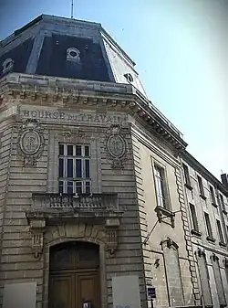Photographie grand angle en couleurs d'un bâtiment de couleur grise sous un ciel bleu