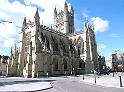 Yellow stone building with large arched windows and a tower.