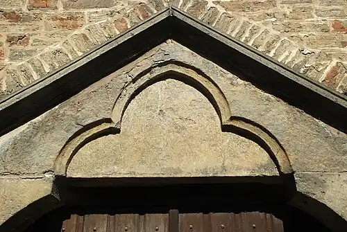 Linteau monolithique en bâtière orné d'un arc trilobé.