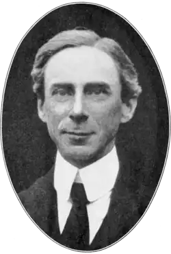 Portrait photographique en noir et blanc, dans un médaillon ovale, d'un homme souriant, portant un haut col rigide et une cravate noire.