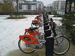 Vélos orange alignés, petite couche de neige blanche qui recouvre le sol.