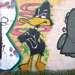 Photo montrant un mur avec un graffiti du canard Daffy Duck, en noir et jaune.