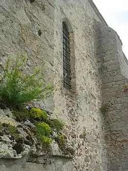Mur de l'église présentant des ouvertures étroites typiques des églises du XIIIe&nbsp;siècle.