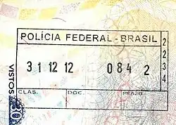Photographie en couleurs, représentant un tampon des services de l'immigration brésilienne, sur un passeport.