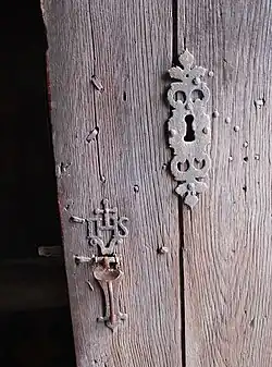 Détail de la serrure en fer forgé portant le monogramme IHS  abréviation de Jésus en grec.