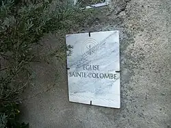 Le nom de l'église Sainte-Colombe inscrit sur une plaque en marbre blanc.