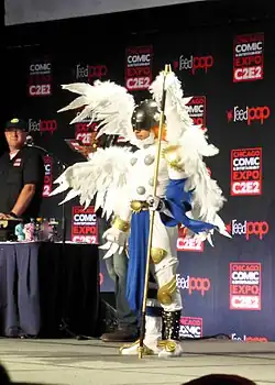 Costume d'ange blanc à six ailes, avec des ornements dorés et un vêtement bleu.