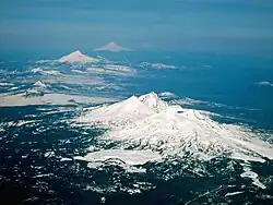 Plusieurs montagnes enneigées photographiées en enfilade et se perdant au loin dans la brume.