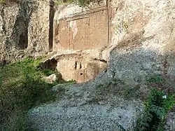 Façade d'une tombe creusée dans la falaise avec une fausse porte en forme de T gravée dessus.
