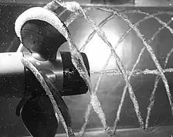 Photo noir et blanc d'une hélice et des bulles créées par cavitation dans l'eau.