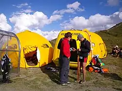 Deux tentes igloo de couleur jaune, sur un col montagneux.