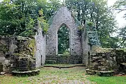 Photographie montrant l'intérieur d'une chapelle en ruine, entourée de végétations.
