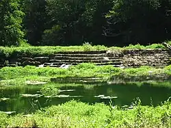 Photo montrant un grand barrage fait de grosses pierres de taille montées en gradins.