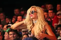 Une femme blonde mal maquillé portant des lunettes noires.