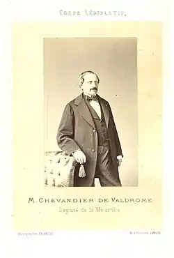 Un homme de trois-quart face pose pour une photographie, en jaquette.