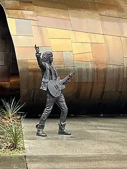Photographie d'une statue d'un homme debout tenant une guitare.