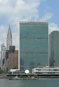 Photo représentant U Thant Island, avec le Chrysler Building et le siège des Nations unis en arrière plan. L'île est peu visible du fait de sa taille modeste.