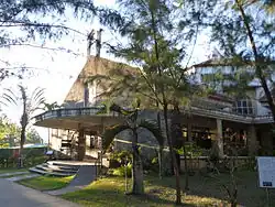 Photographie de la façade d'une église entourée de végétation tropicale