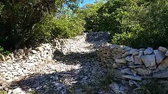 Chemin en garrigue, bordé de murs de pierres à Claret.