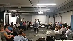 photo d'une salle dans une entreprise où des personnes sont assises en cercle.