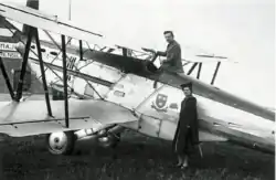 Photographie noir et blanc d'un homme debout dans le cockpit d'un avion et d'une femme, debout, appuyé contre le fuselage.
