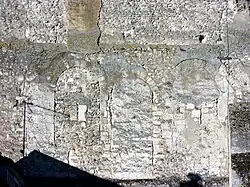 Photographie en couleurs d'un mur dont les baies ont été murées.