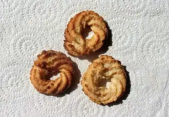 Photographie en couleurs de petits biscuits troués en leur centre.