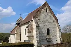 Le chœur de l'église en pierre calcaire avec une ouverture de style roman.