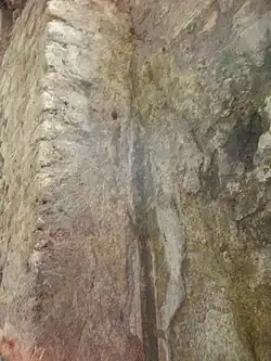 Détail d'un mur avec le reste de stuc et un filet de couleur.