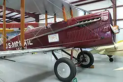 Avion biplan assez massif, peint en bordeaux, exposé dans un musée.