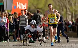 Un coureur donnant une tape amicale à un handisport au passage du ravitaillement du Trocadéro lors de l'édition 2014.