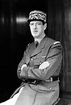 Charles de Gaulle assis en uniforme regardant vers la gauche avec les bras croisés.